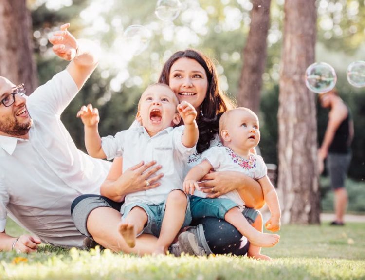 Joyful family enjoying a sunny day in the park while playing with bubbles.